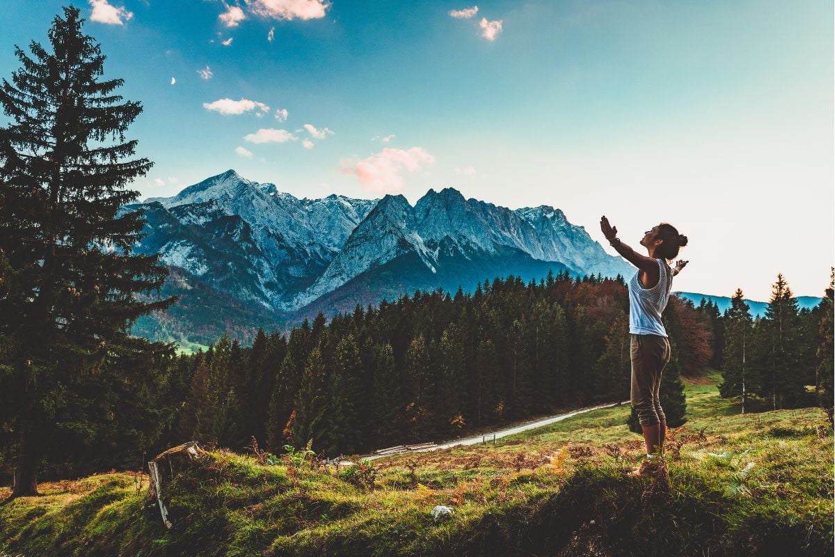 Person with arms outstretched facing towering mountains during a digital detox nature retreat at Basecamp Smokey Mountains.