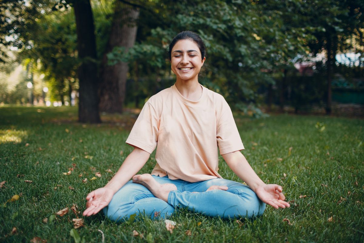 Woman meditating with a smile on her face, utilizing relaxation techniques at Basecamp Smoky Mountains nature therapy session. 