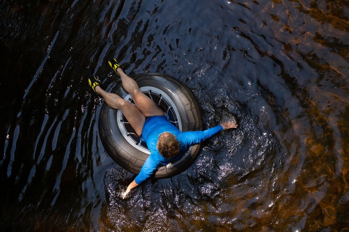 A person enjoys the benefits of nature on a rubber tire in water.